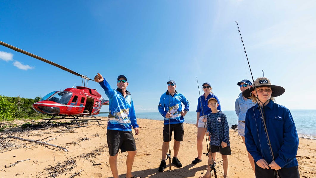 People standing in front of helicopter with fishing rods