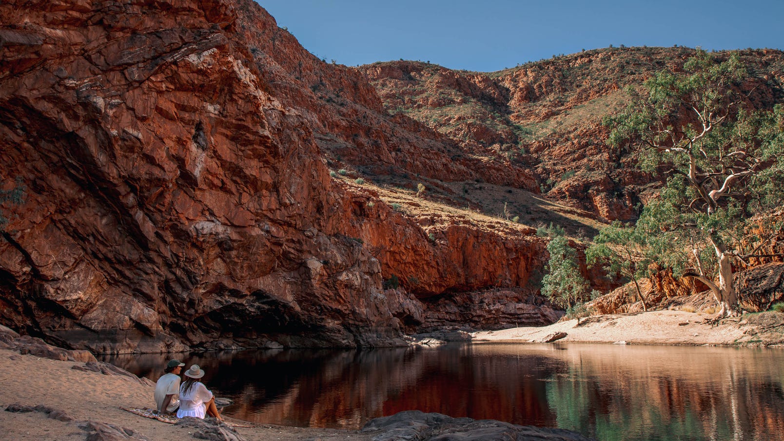 young couple sitting at ormiston gorge talking and taking in the scenic views