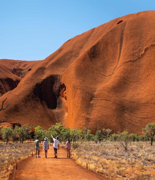 Visitors walking together at the base of Uluru