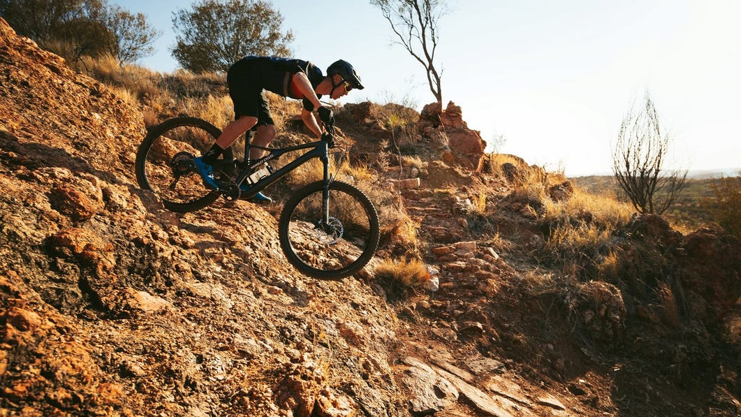 Mountain biking riding down rocky hill